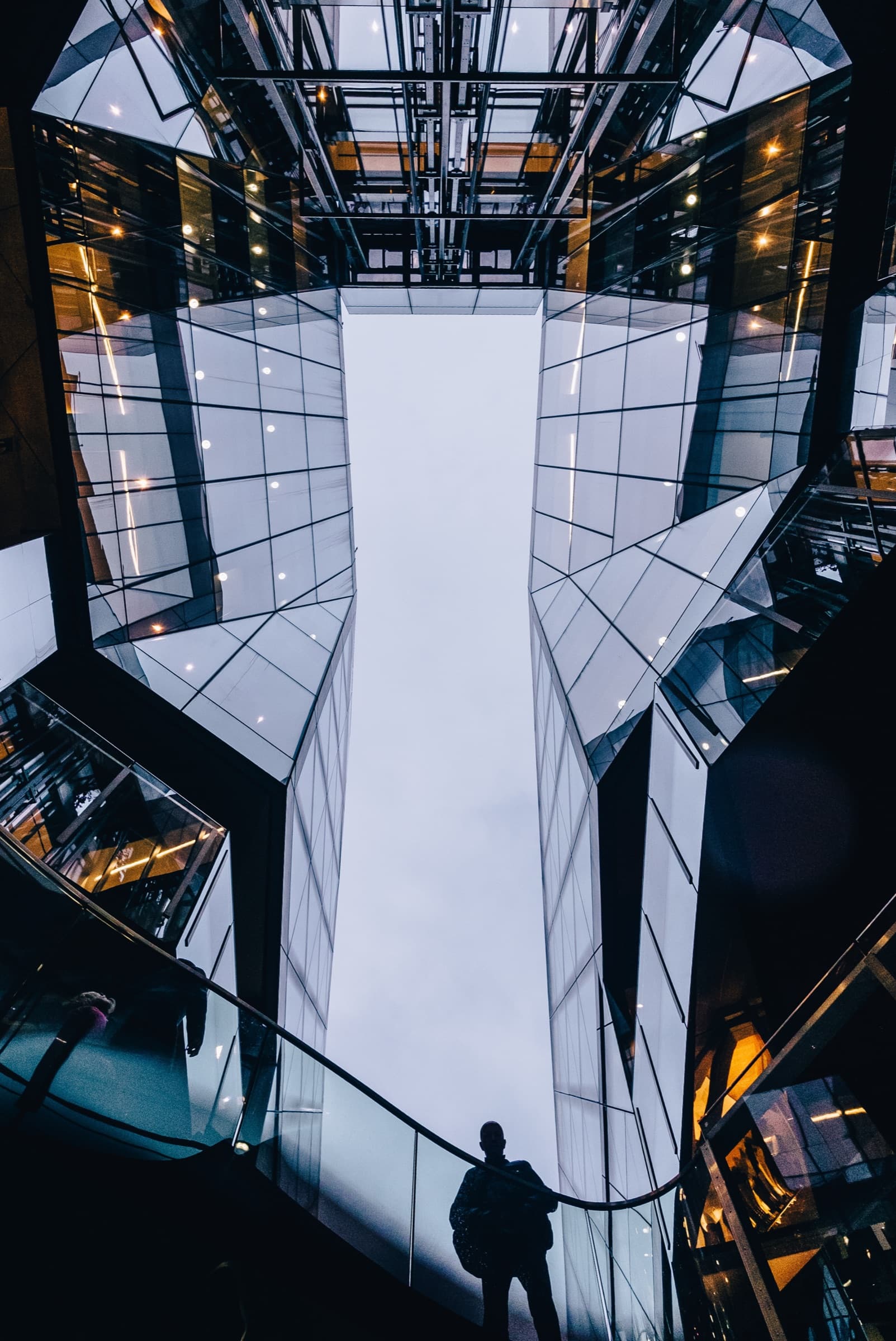 Contre-plongée sur l’atrium vitré d’un immeuble de bureaux.